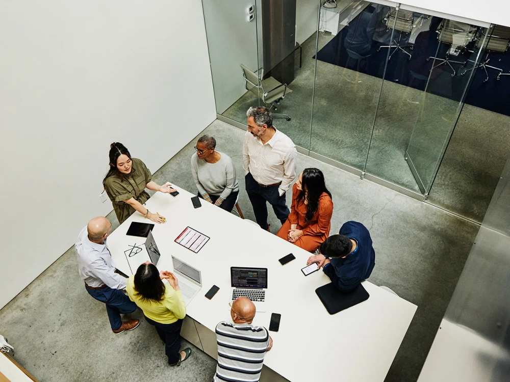 Group of seven people in a meeting around a white table in a modern office