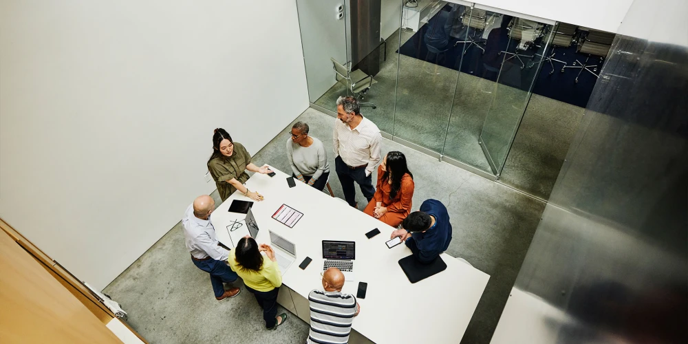 Group of seven people in a meeting around a white table in a modern office