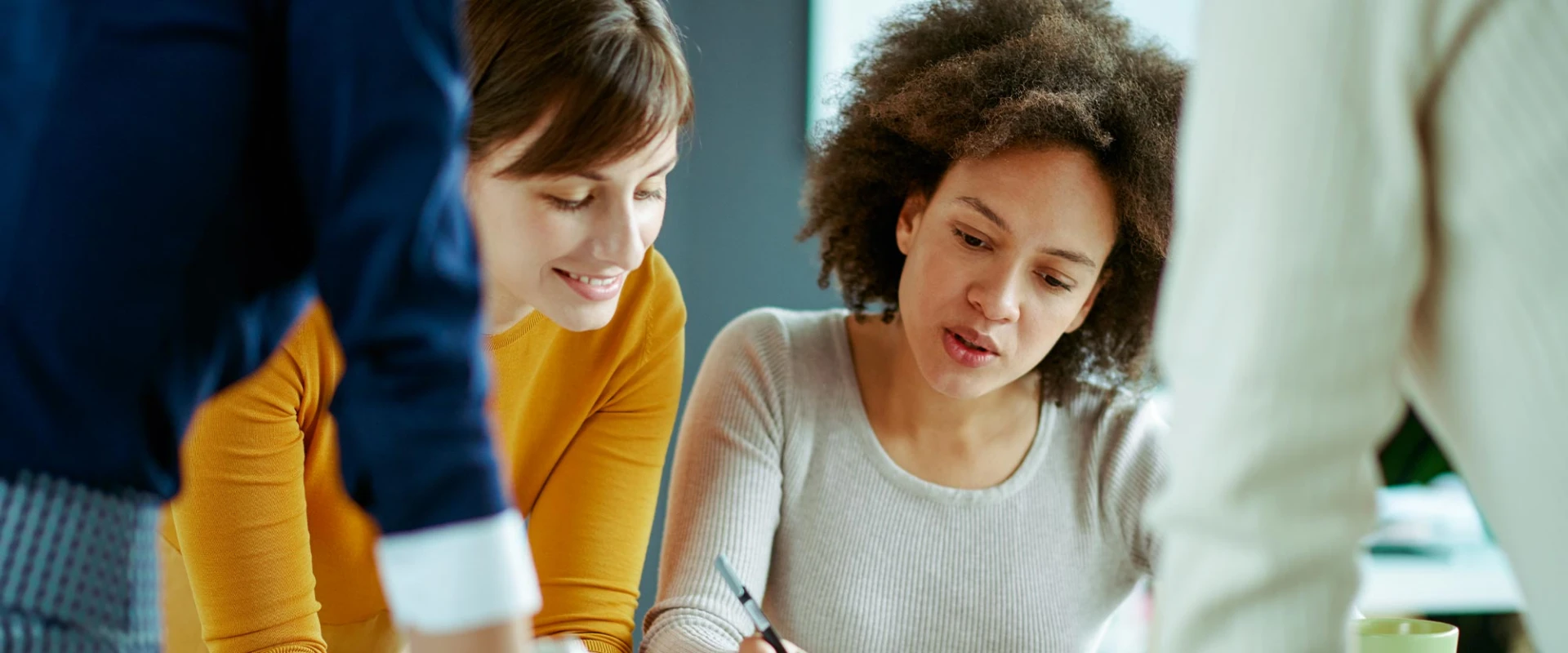 Three colleagues discussing a document at a table in an office.
