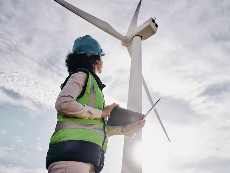 Engineer in safety gear looking at a wind turbine
