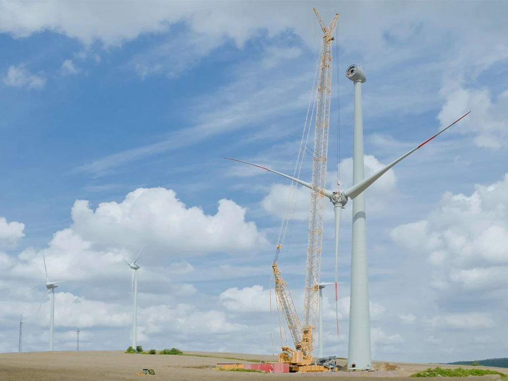 Montage eines Windrades mit einem großen Kran unter wolkenverhangenem Himmel