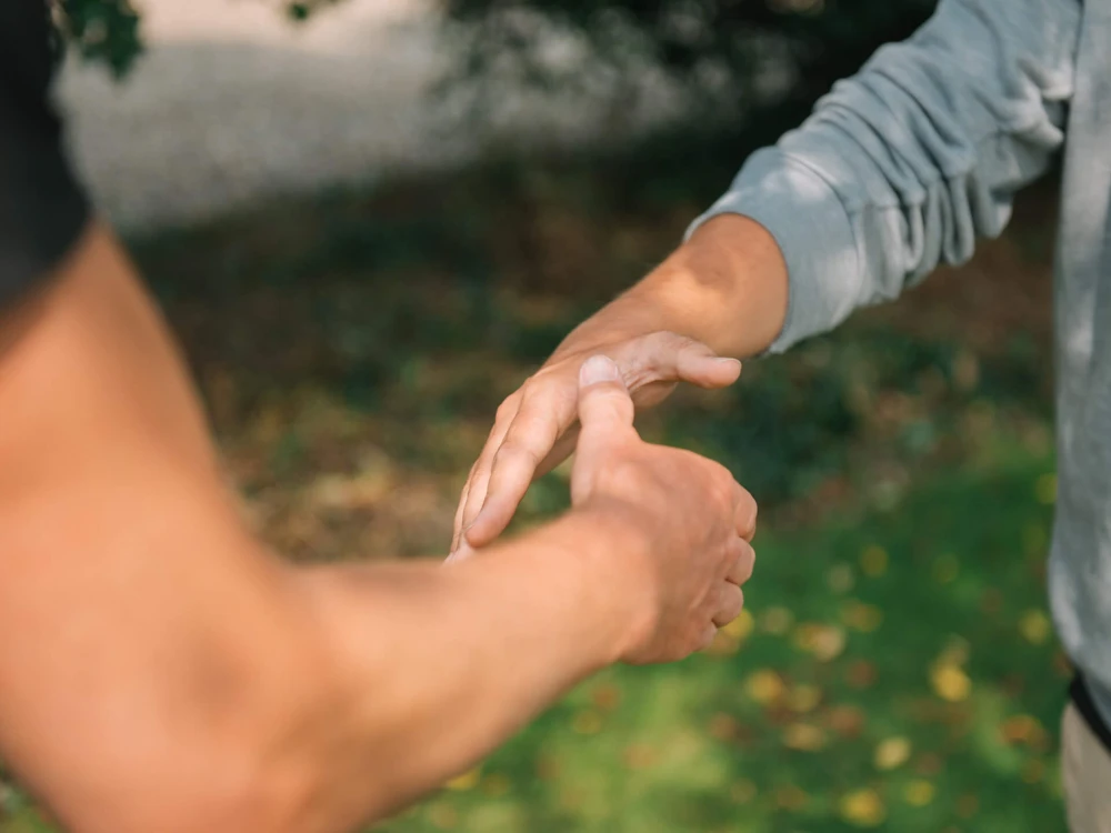Zwei Personen geben sich die Hände in einem freundschaftlichen Handschlag im Freien