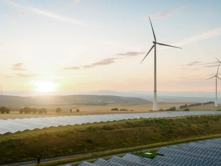 Landschaft mit Windrädern und Solarpaneelen bei Sonnenuntergang
