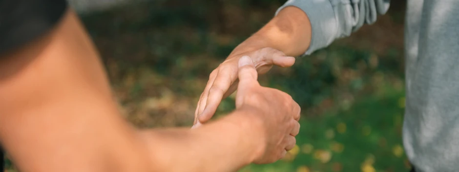Zwei Personen halten sich im Freien an den Händen
