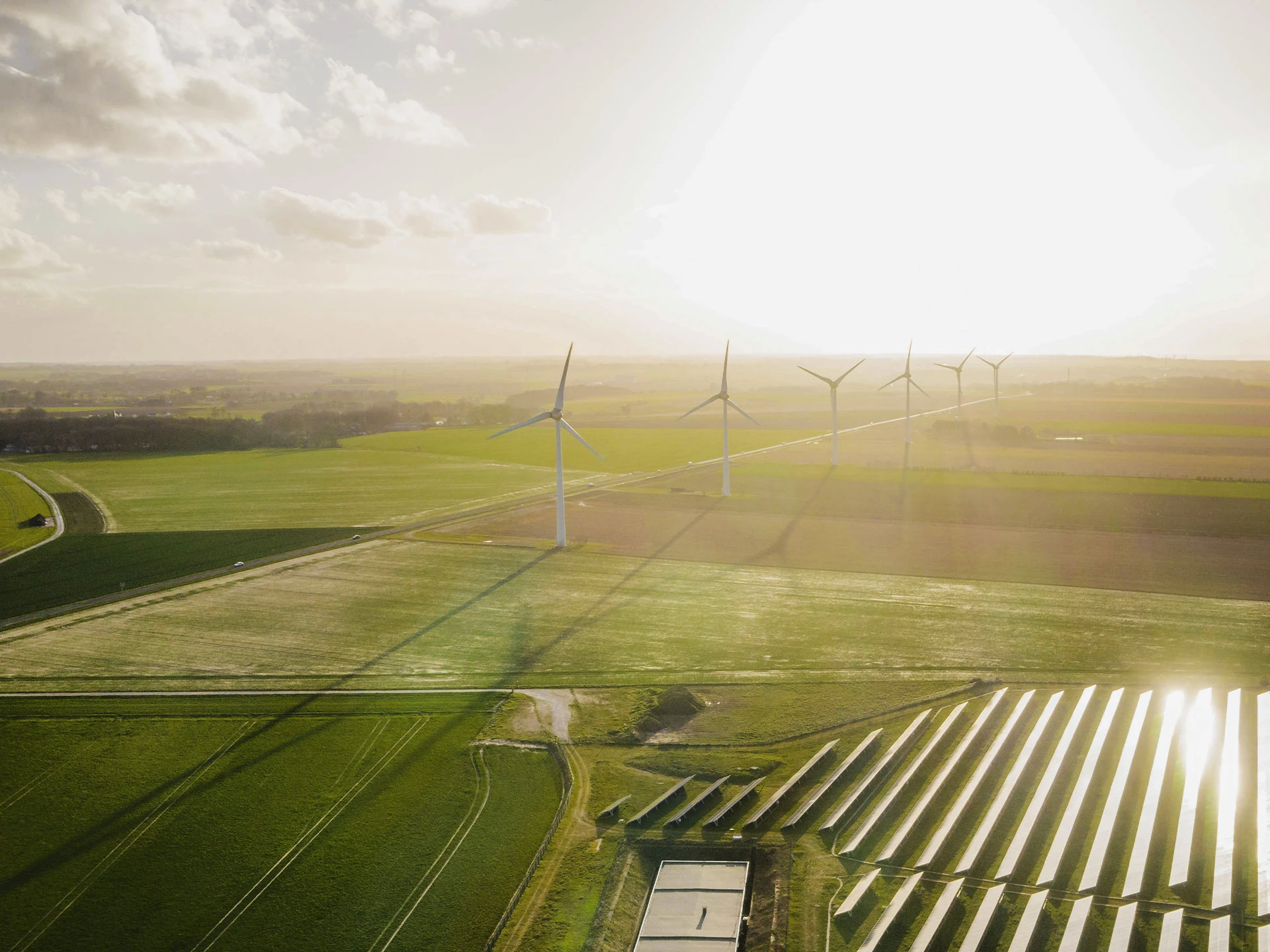 Luftaufnahme von Windkraftanlagen und Solarmodulen auf einem Feld bei Sonnenuntergang