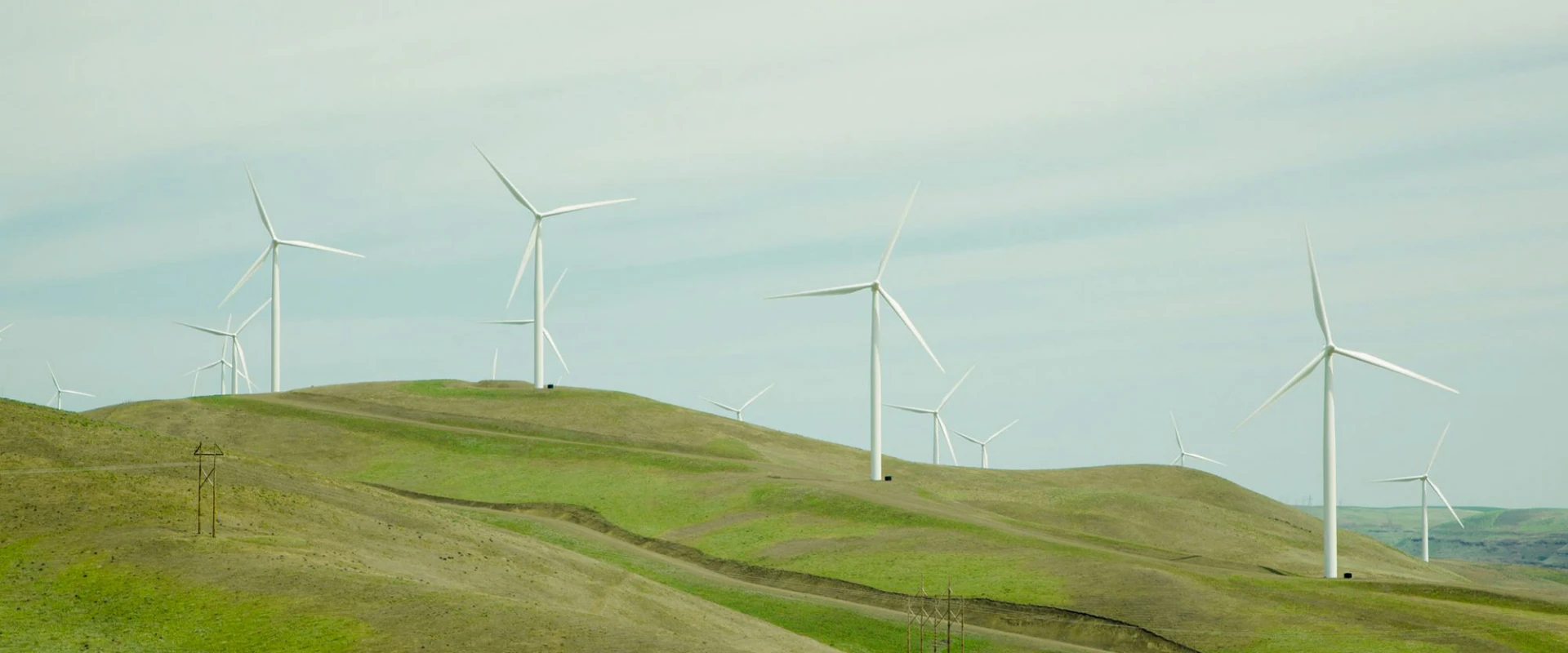 Windkraftanlagen auf grünen Hügeln unter einem klaren Himmel