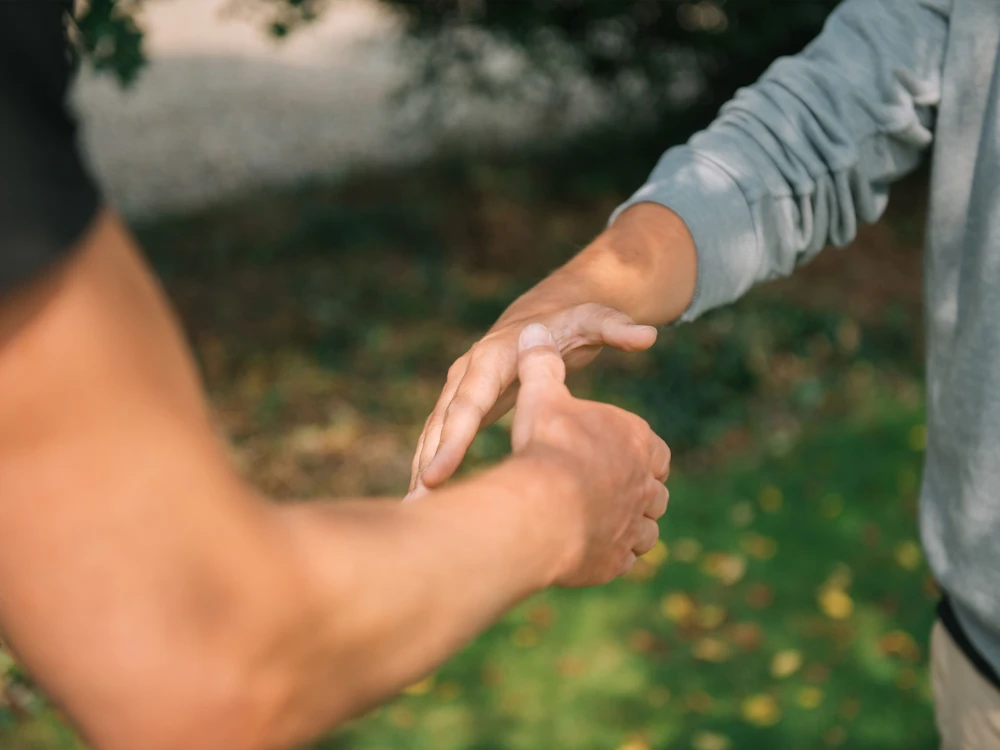 Zwei Personen führen einen Handschlag im Freien durch