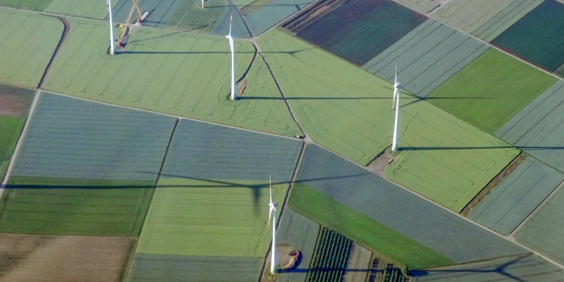 Aerial view of wind turbines and agricultural fields in various shades of green