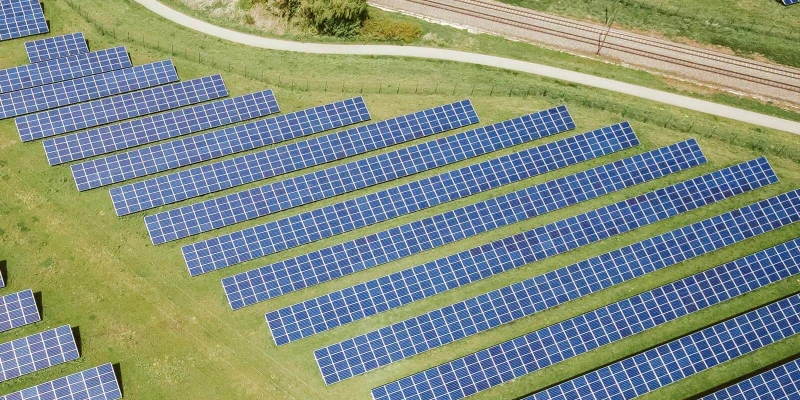 Aerial view of a solar farm with numerous photovoltaic panels on a grassy field