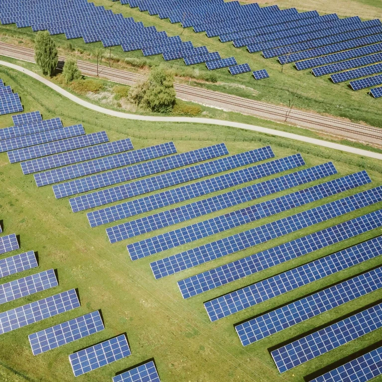 Luftaufnahme eines Solarparks mit zahlreichen Photovoltaik-Paneelen auf einer Wiese