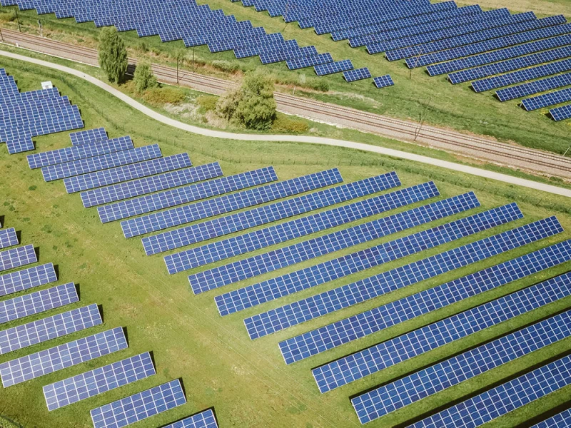 Luftaufnahme eines großen Solarparks mit zahlreichen Photovoltaik-Modulen auf einer grünen Wiese
