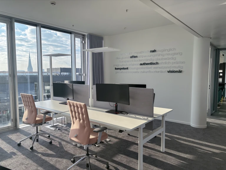 Modernes Büro mit zwei Arbeitsplätzen, großen Fenstern und Blick auf eine Stadt