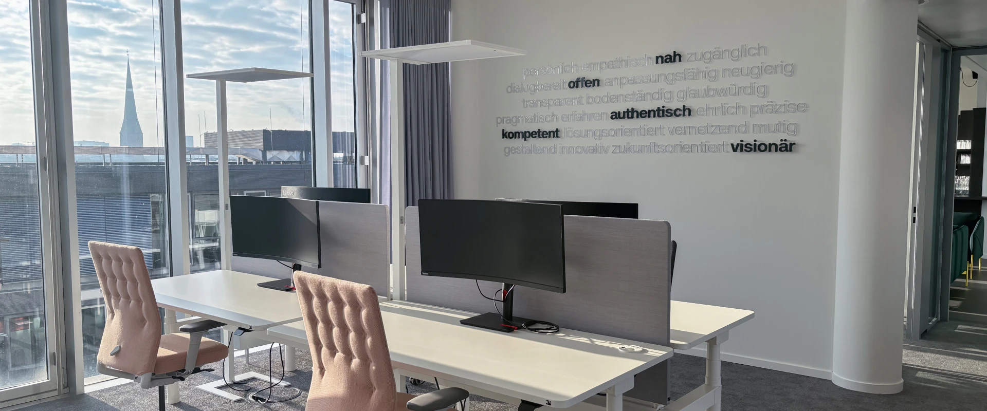 Modernes Büro mit zwei Arbeitsplätzen, großen Fenstern und Blick auf eine Stadt