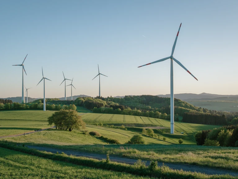 Landscape with wind turbines on green hills at sunset