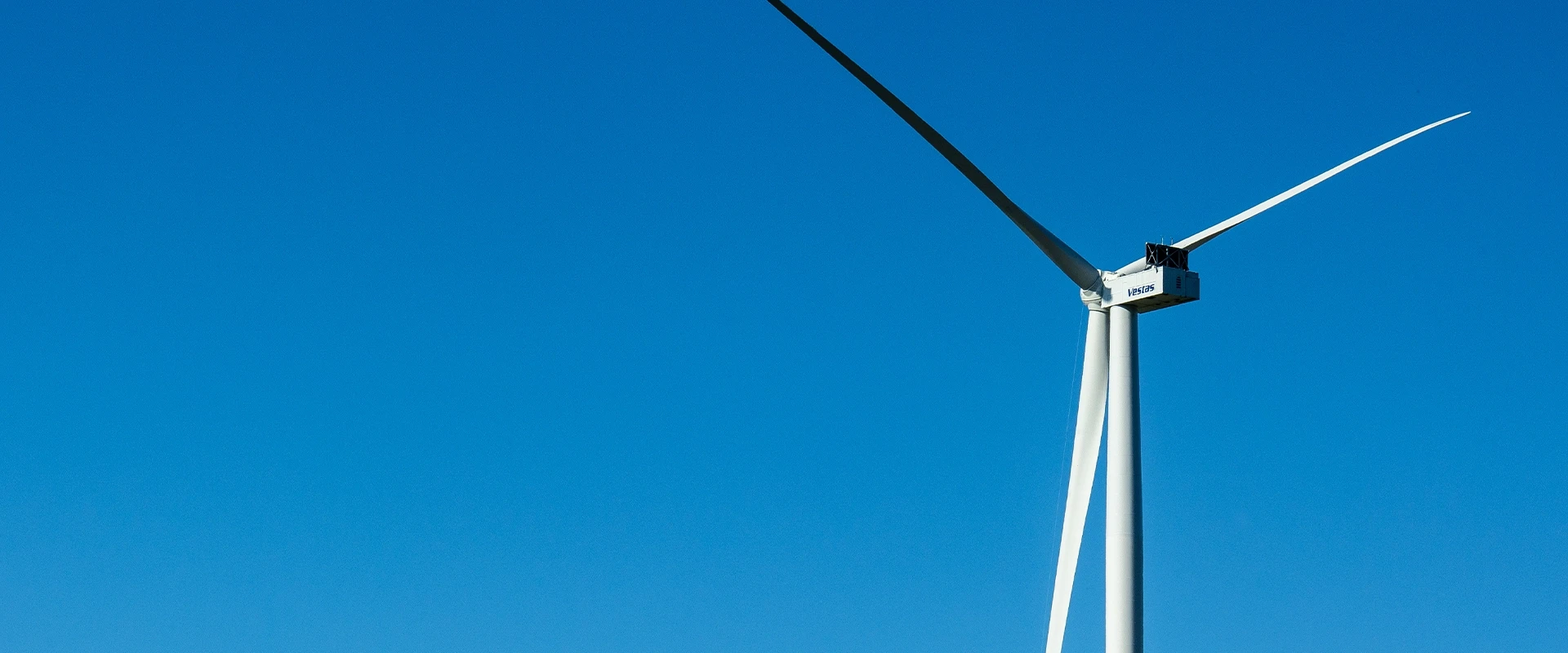 Ein einzelnes Windrad vor klarem, blauem Himmel – Symbol für erneuerbare Energien und nachhaltige Stromerzeugung.