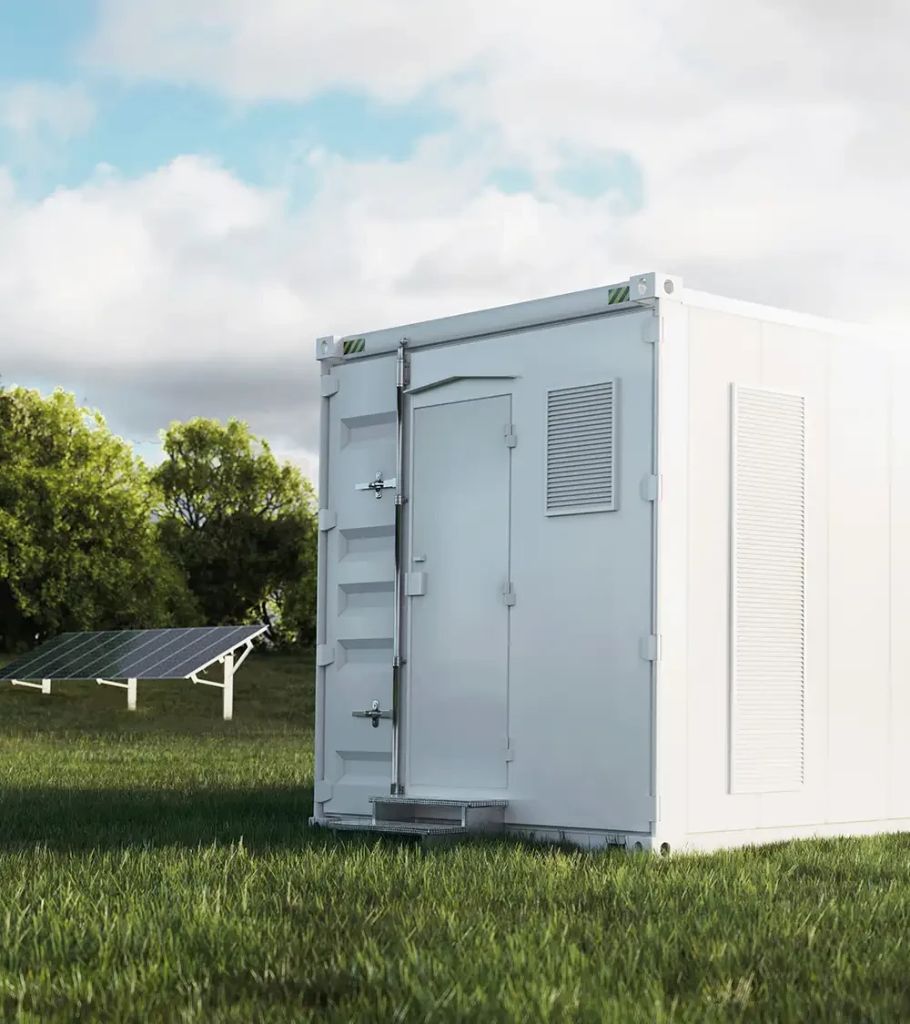 Ein großer grauer Metallcontainer auf einer grünen Wiese mit Solarmodulen im Hintergrund