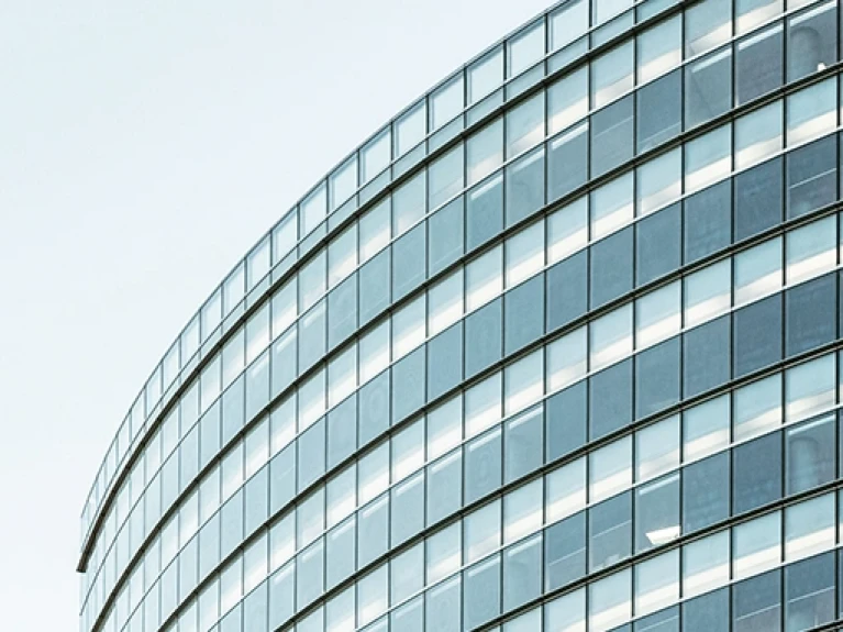 Moderne Glasfassade eines Bürogebäudes mit gekrümmter Struktur unter klarem Himmel