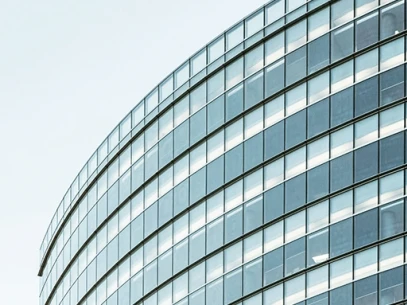 Moderne Glasfassade eines Bürogebäudes mit gekrümmter Struktur unter klarem Himmel